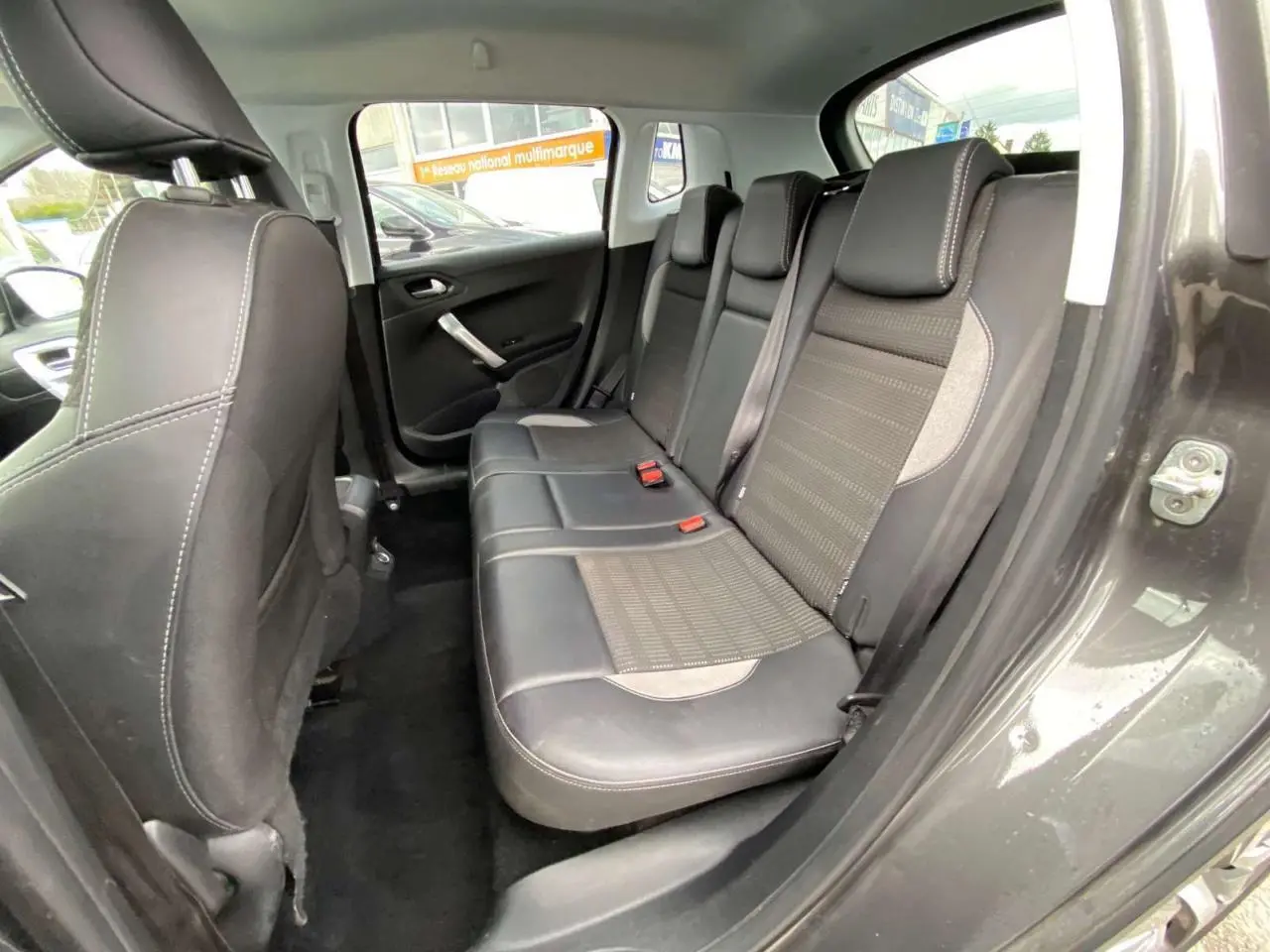 Vue intérieure du siège arrière droit du Peugeot 2008 gris platinium, montrant la banquette en cuir et tissu avec ceintures de sécurité.