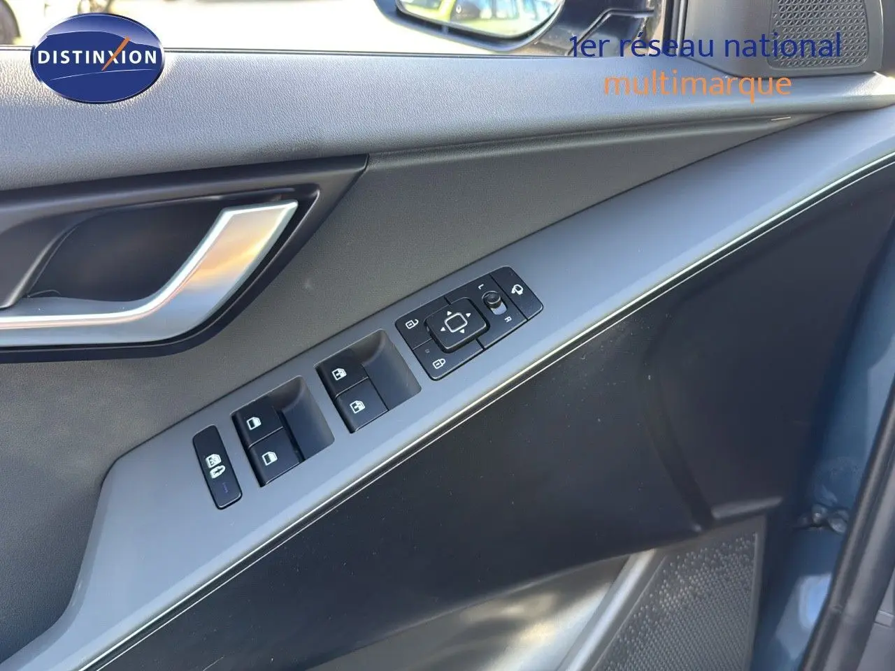 Panneau de porte côté conducteur du Kia Niro bleu minéral métal 2025 avec commandes de vitres et rétroviseurs.