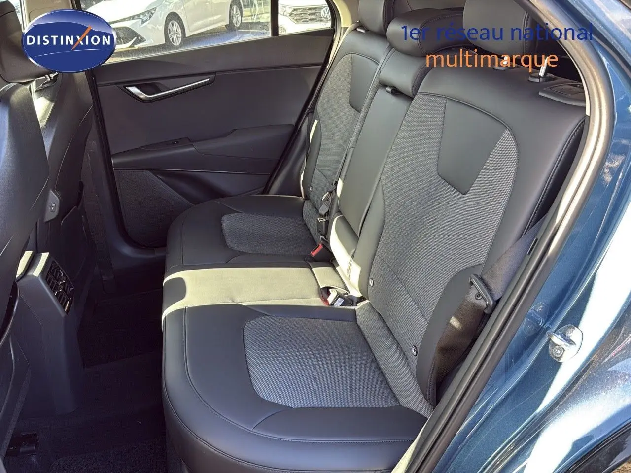 Intérieur arrière du Kia Niro 2025 bleu minéral métal, montrant les sièges en cuir noir et tissu gris côté droit.