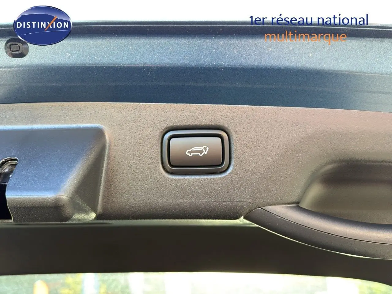 Bouton d'ouverture électrique du coffre sur la partie intérieure du hayon bleu minéral métal d'un Kia Niro 2025 hybride rechargeable.