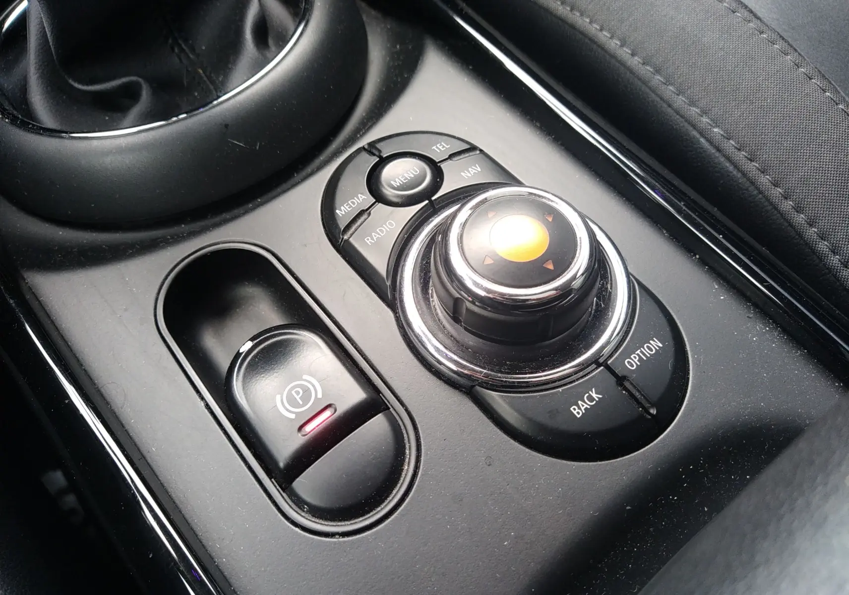 Gros plan sur la molette de commande centrale noire et le frein à main électrique dans l'habitacle d'une MINI Clubman 2017.