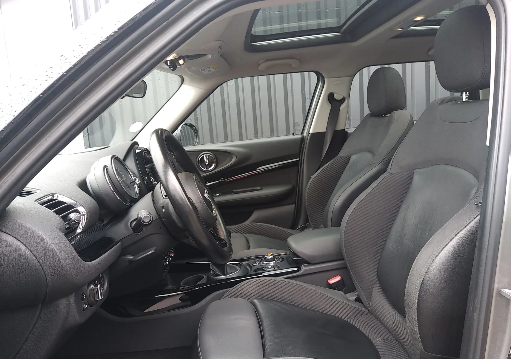 Intérieur noir de la MINI CLUBMAN F54 2017, vue côté conducteur avec volant, sièges en cuir et toit ouvrant panoramique.