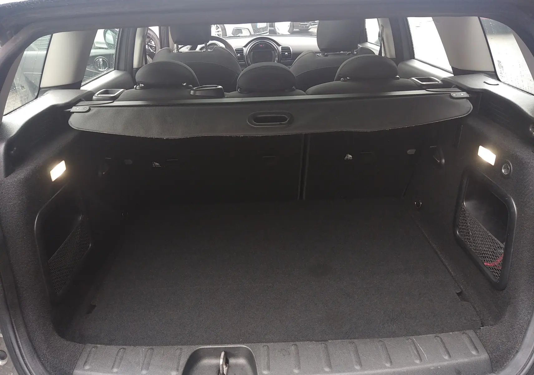 Coffre ouvert d'une MINI CLUBMAN F54 Silver Metal, vue arrière intérieure montrant l'espace de chargement et les sièges noirs.