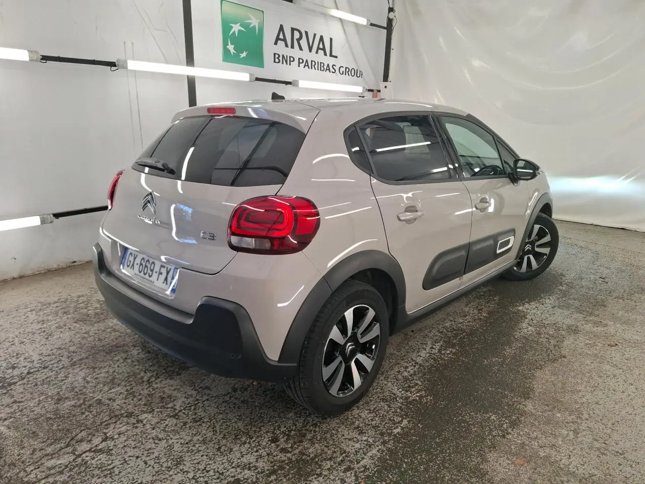 Vue 3/4 arrière droit d'une Citroën C3 beige clair avec protections latérales noires et jantes alliage diamantées.