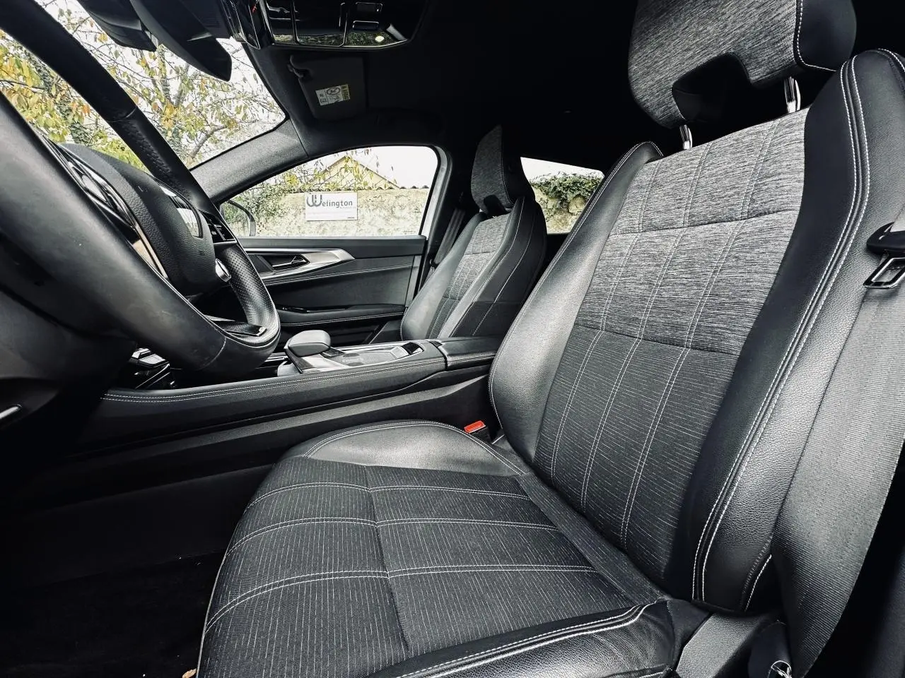 Intérieur de la Renault Austral 2024 vu côté conducteur, sièges tissu gris avec surpiqûres blanches et volant noir.