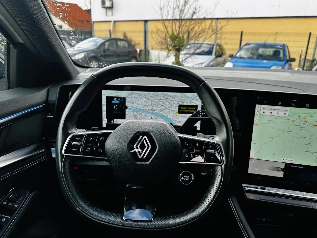 Vue intérieure centrée sur le volant noir de la Renault Austral 2024 avec tableau de bord numérique et écran tactile.