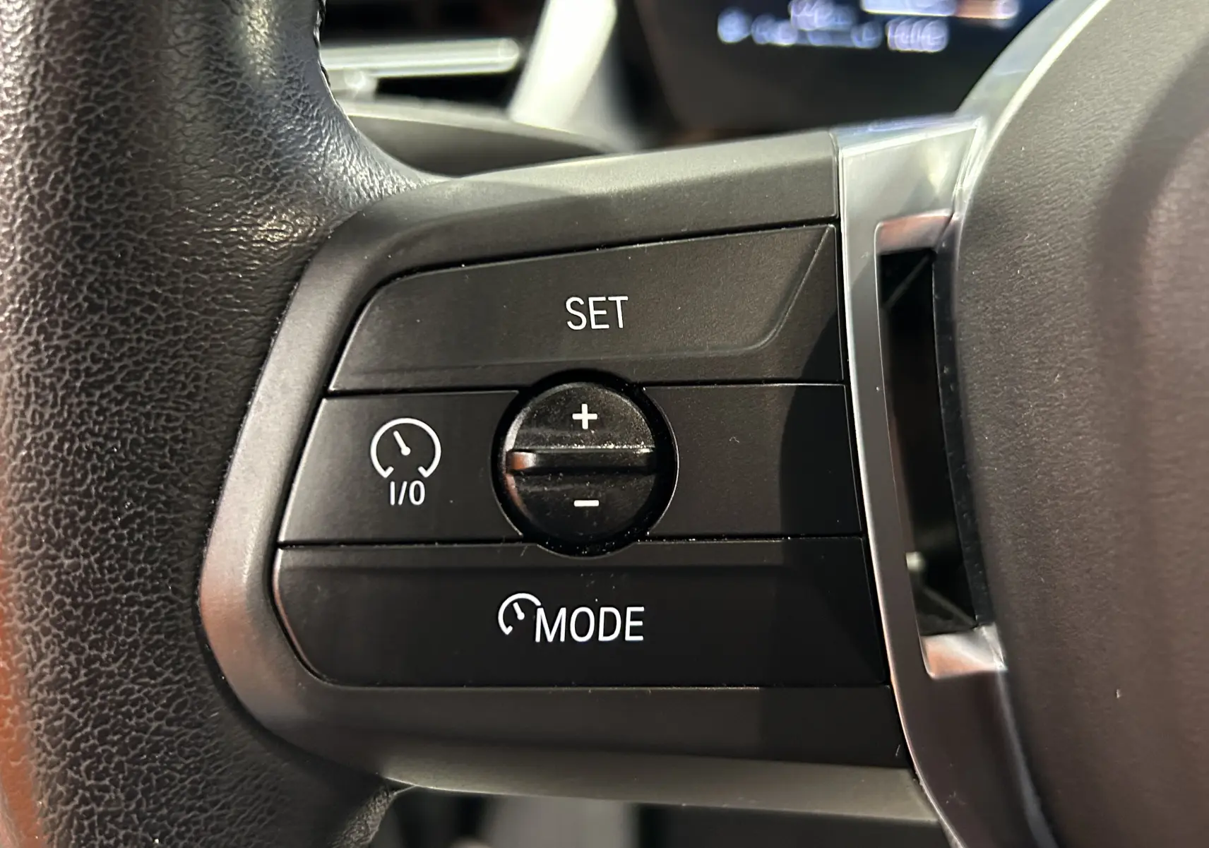 Gros plan sur les commandes de régulateur de vitesse au volant d’une BMW Série 2 Active Tourer blanche.