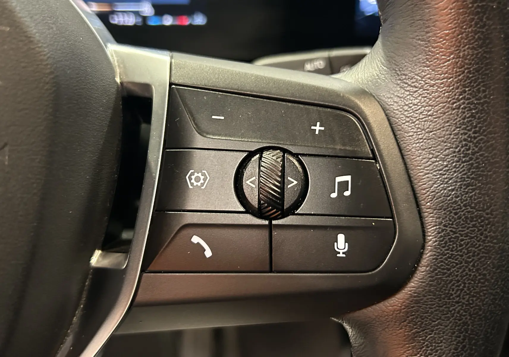 Gros plan sur les commandes du volant à droite en cuir noir de la BMW Série 2 Active Tourer blanche, avec boutons multifonctions.