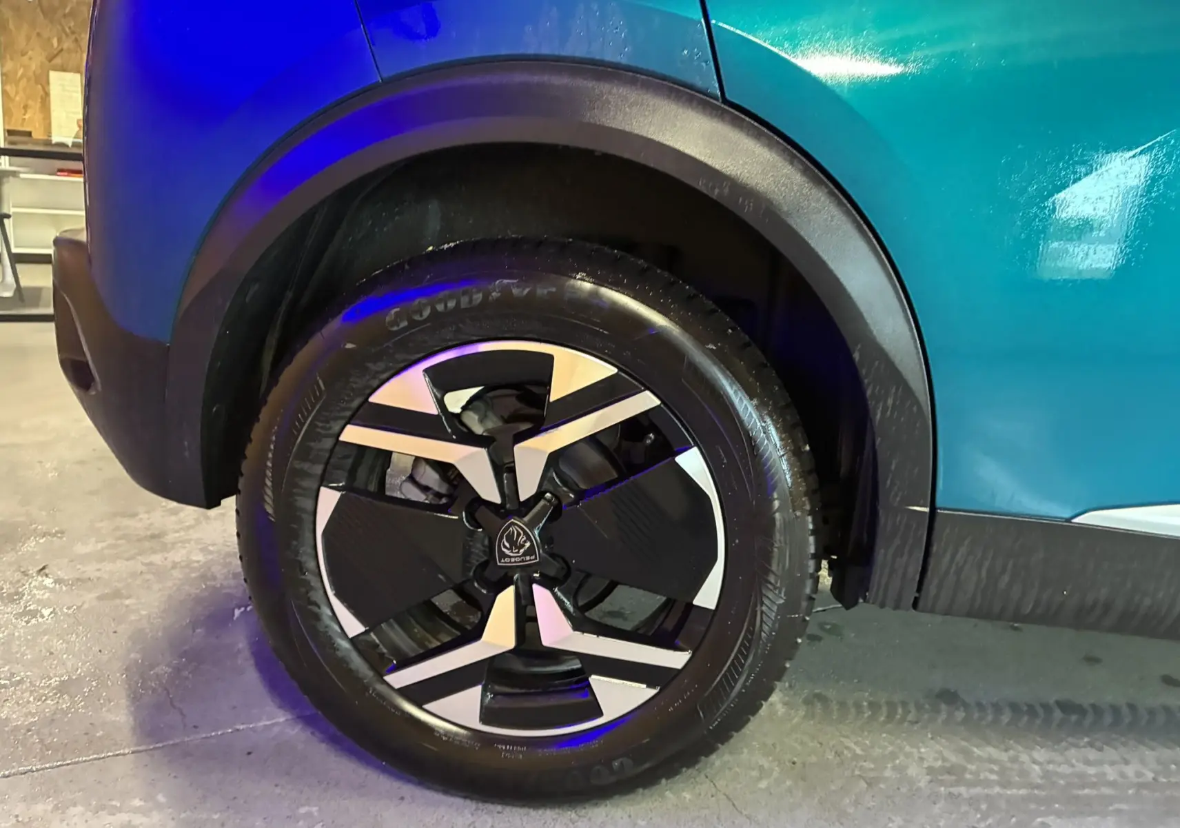 Gros plan sur la roue arrière droite du Peugeot 2008 bleu 2025, mettant en valeur la jante au design moderne bicolore.