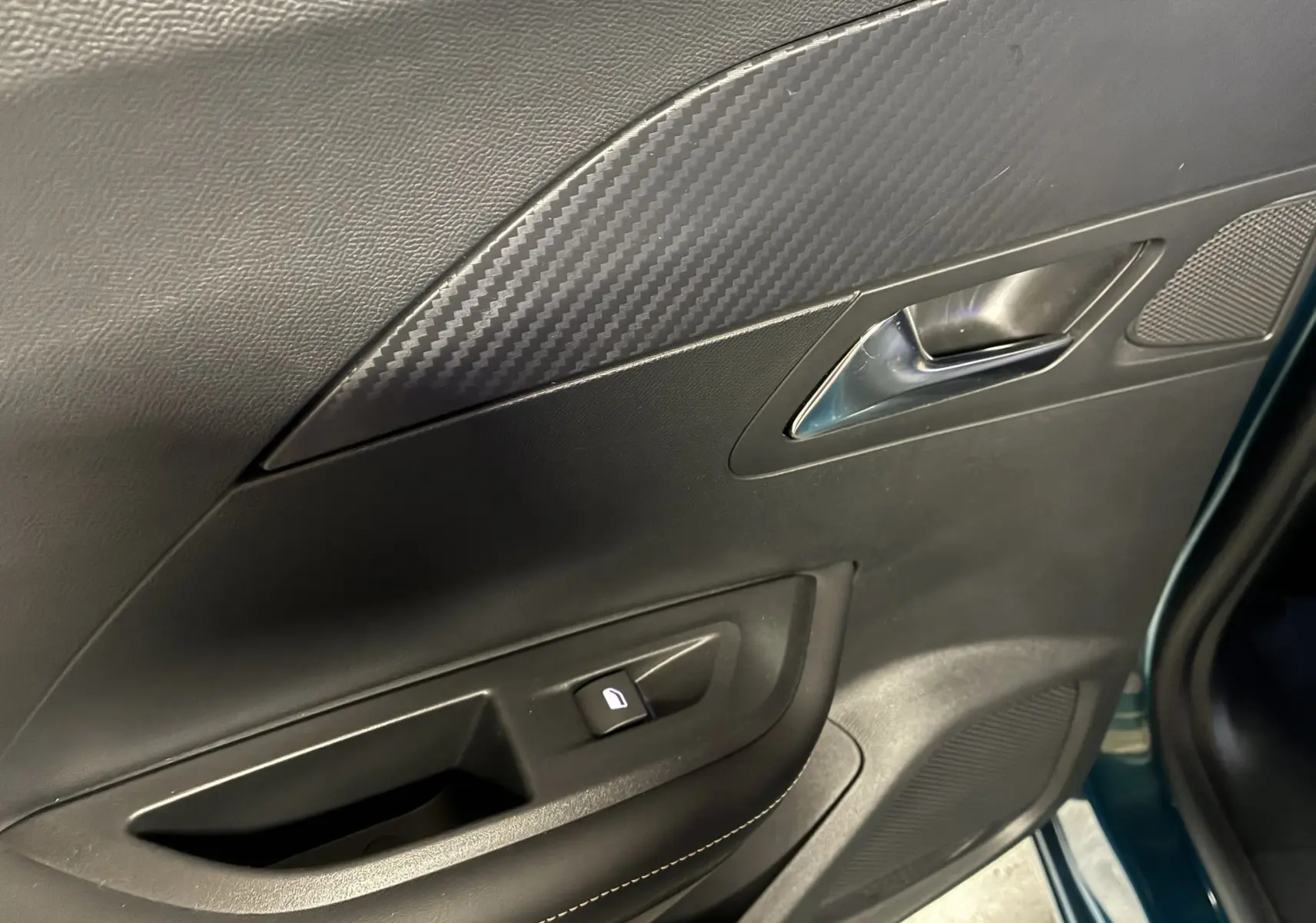 Vue rapprochée de la porte intérieure côté gauche du Peugeot 2008 bleu, avec poignée argentée et bouton de verrouillage.