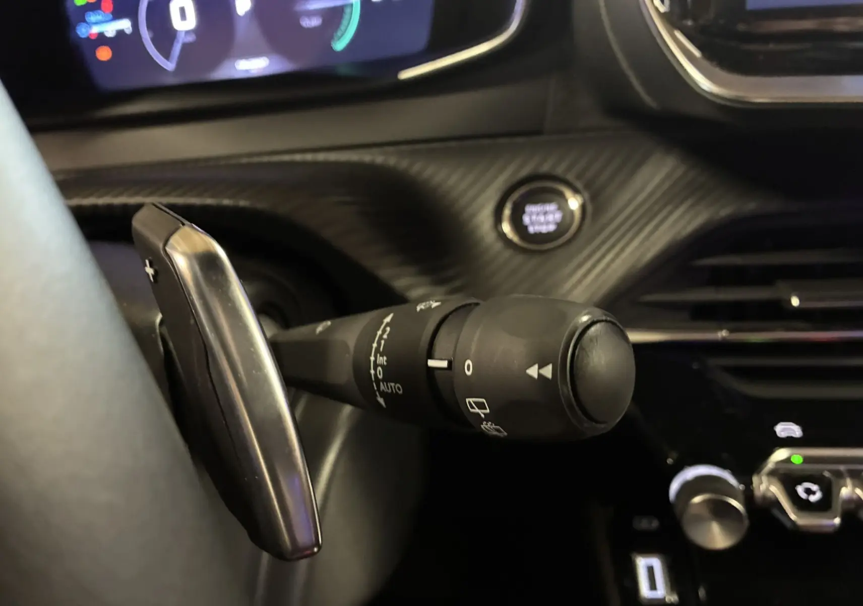 Gros plan sur la commande d’essuie-glace et palette de changement de vitesse dans l’habitacle noir du Peugeot 2008 hybride 2025.