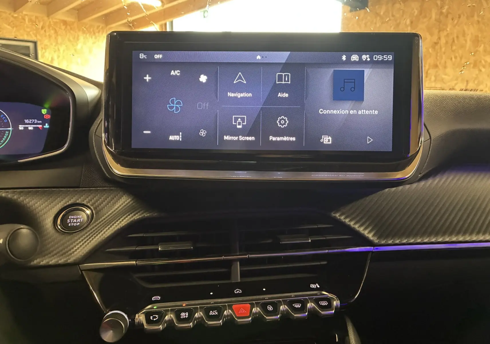 Vue rapprochée du tableau de bord noir du Peugeot 2008 1.2 Hybrid 136 avec écran tactile central et bouton start/stop.