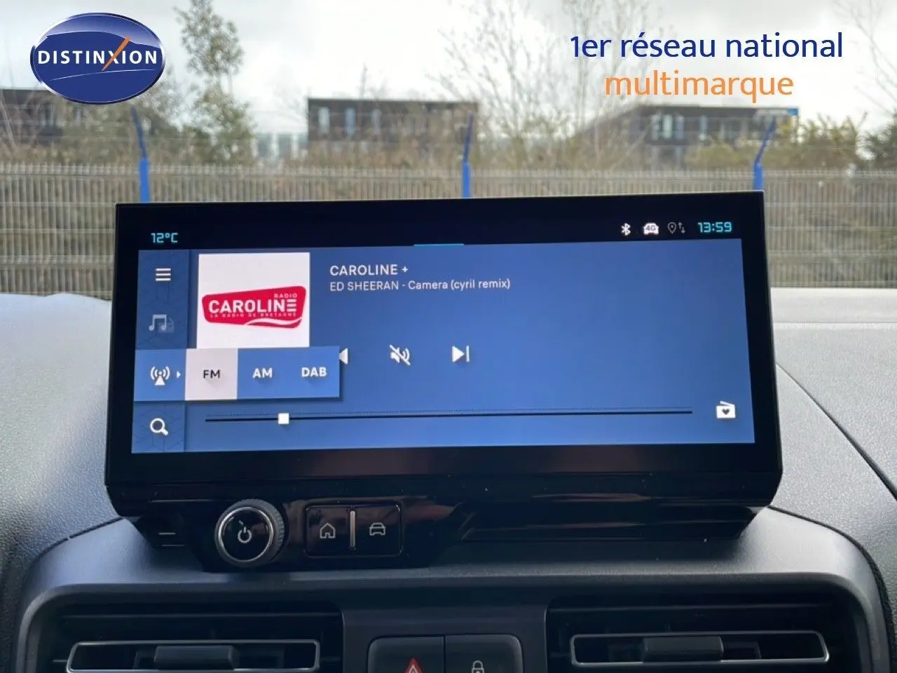 Écran tactile central du tableau de bord du Citroën Berlingo blanc, affichant une radio FM avec station Caroline.