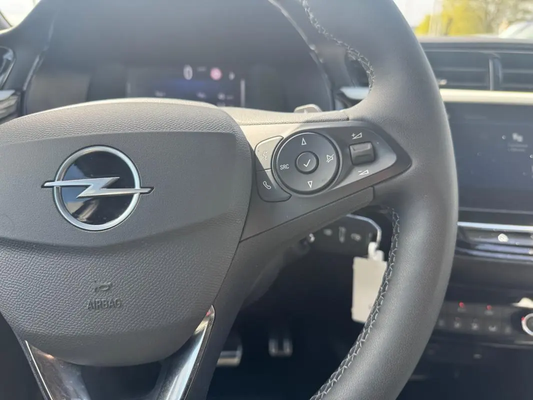 Gros plan sur le volant noir de l’Opel Corsa 2025, avec commandes intégrées et logo Opel central visible.