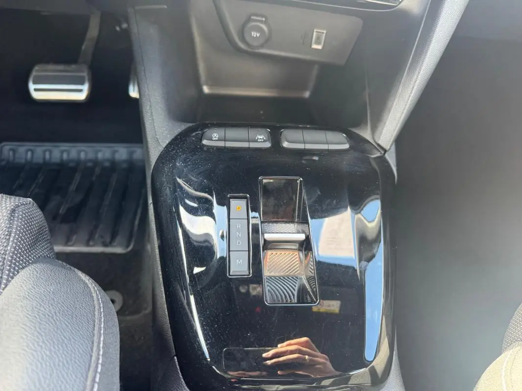 Gros plan sur la console centrale noire brillante de l’Opel Corsa 1.2 Turbo Hybrid 2025 avec levier de boîte automatique et boutons de contrôle.