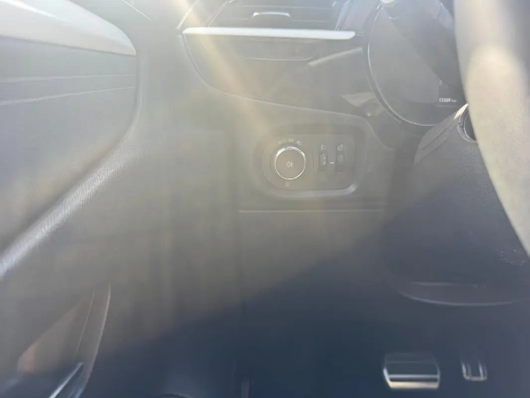 Détail intérieur côté gauche de l’Opel Corsa 2025 noir, montrant les commandes d’éclairage et les pédales en aluminium.