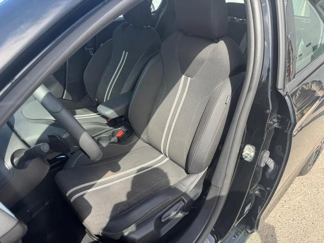 Vue intérieure côté conducteur de l’Opel Corsa 2025 noire, mettant en valeur les sièges tissu avec bandes centrales claires.