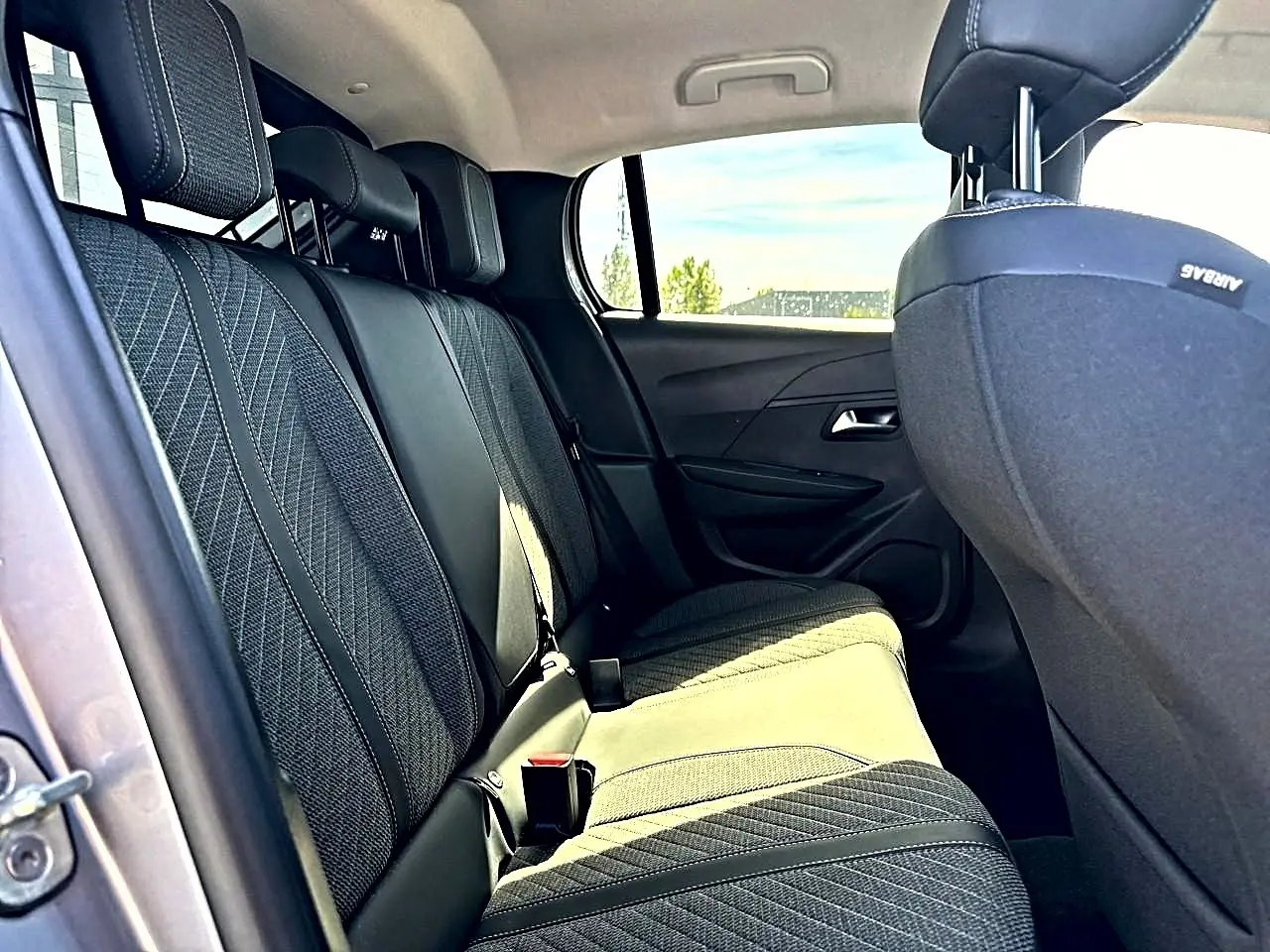 Vue intérieure côté gauche des sièges arrière en tissu gris foncé de la Peugeot 208 1.2 100 Allure 2025.