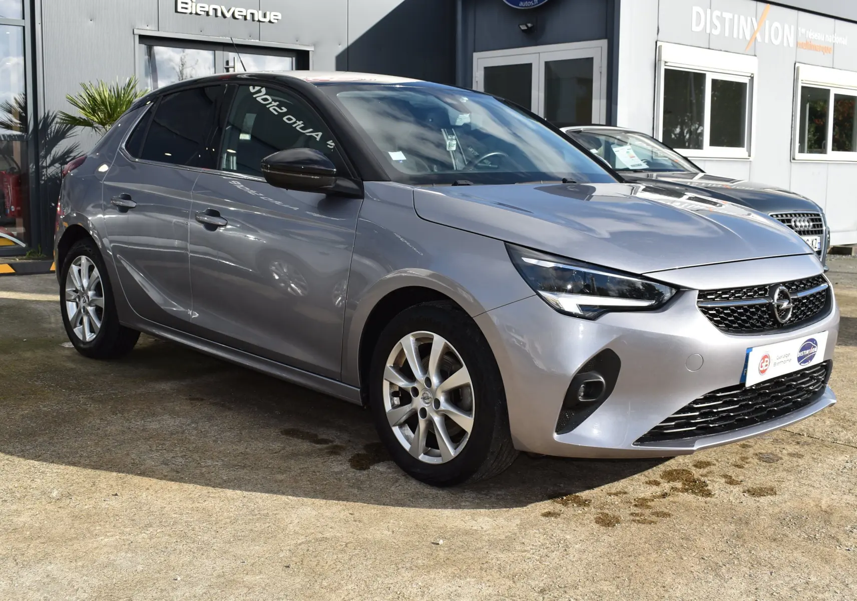 Opel Corsa gris 2021 vue 3/4 avant droit, avec phares LED et jantes alliage sur parking extérieur.