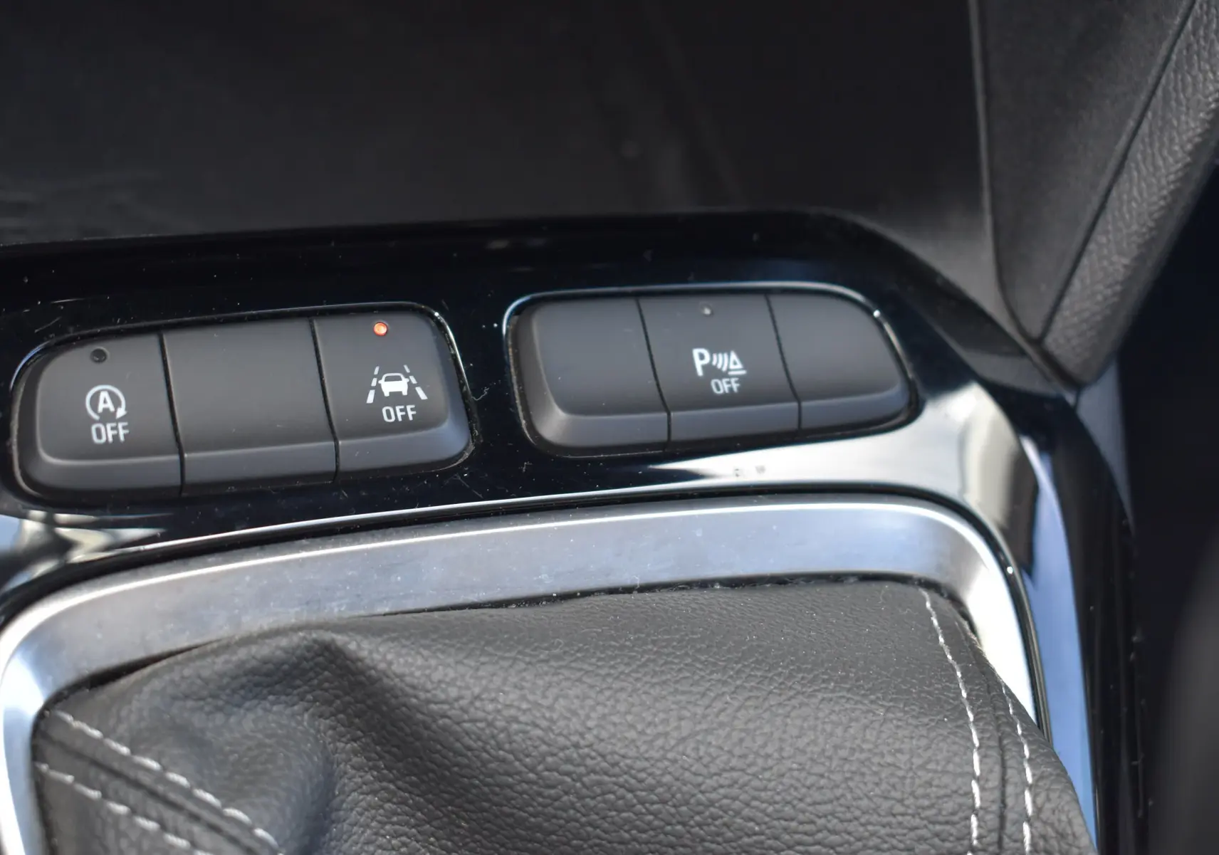 Gros plan sur les boutons de contrôle et soufflet de levier de vitesse en cuir noir de l'Opel Corsa 1.2 Turbo essence.