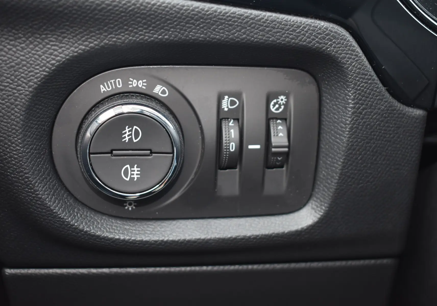 Gros plan sur le panneau de commande des phares de l’Opel Corsa gris 2021 avec réglages d’éclairage et de luminosité.