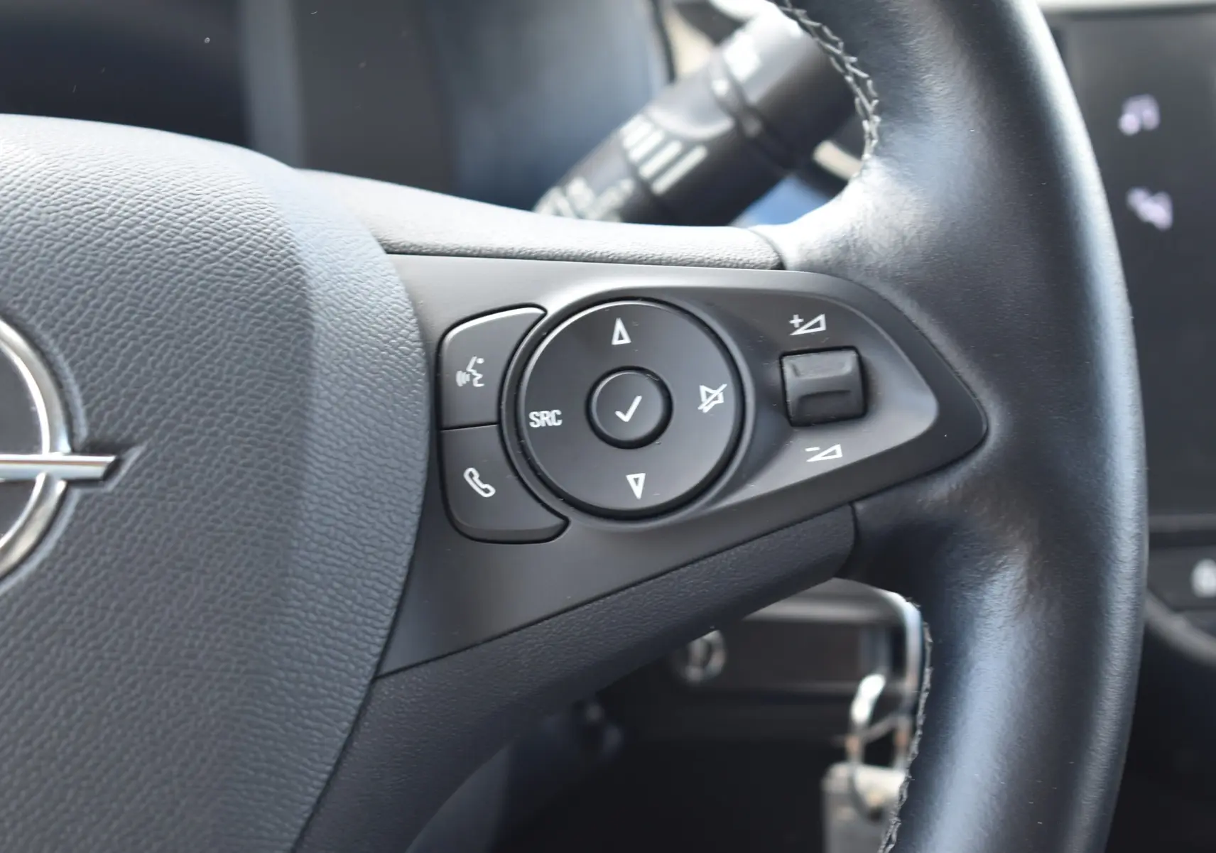 Gros plan sur les commandes du volant noir de l'Opel Corsa gris 2021, version 1.2 Turbo Elegance, avec boutons multifonctions.