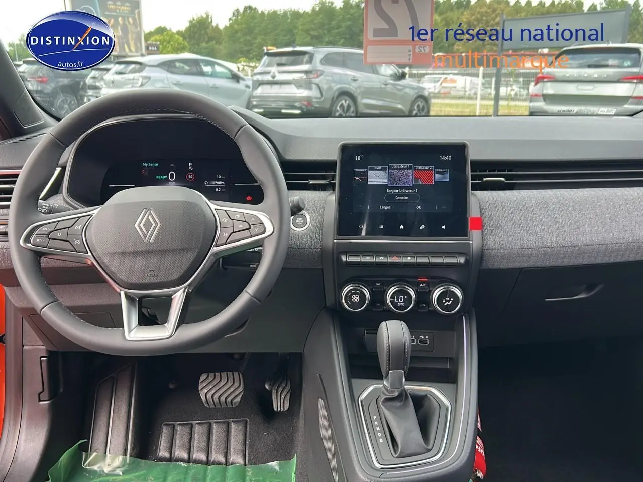 Intérieur avant de la Renault Clio V orange Valencia, volant multifonction et écran tactile central visible.
