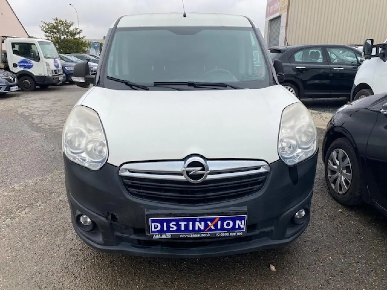 Vue avant d'un Opel Combo blanc avec pare-chocs noir et calandre chromée sur un parking.