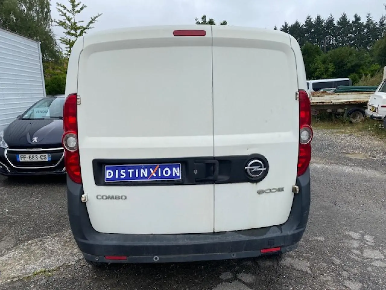 Vue arrière d'un utilitaire Opel Combo blanc avec portes arrière tôlées et logo distinctif sur parking.