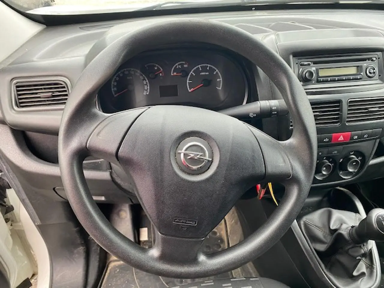 Vue rapprochée du volant Opel Combo L2H1 2016, tableau de bord noir avec autoradio et commandes manuelles visibles.