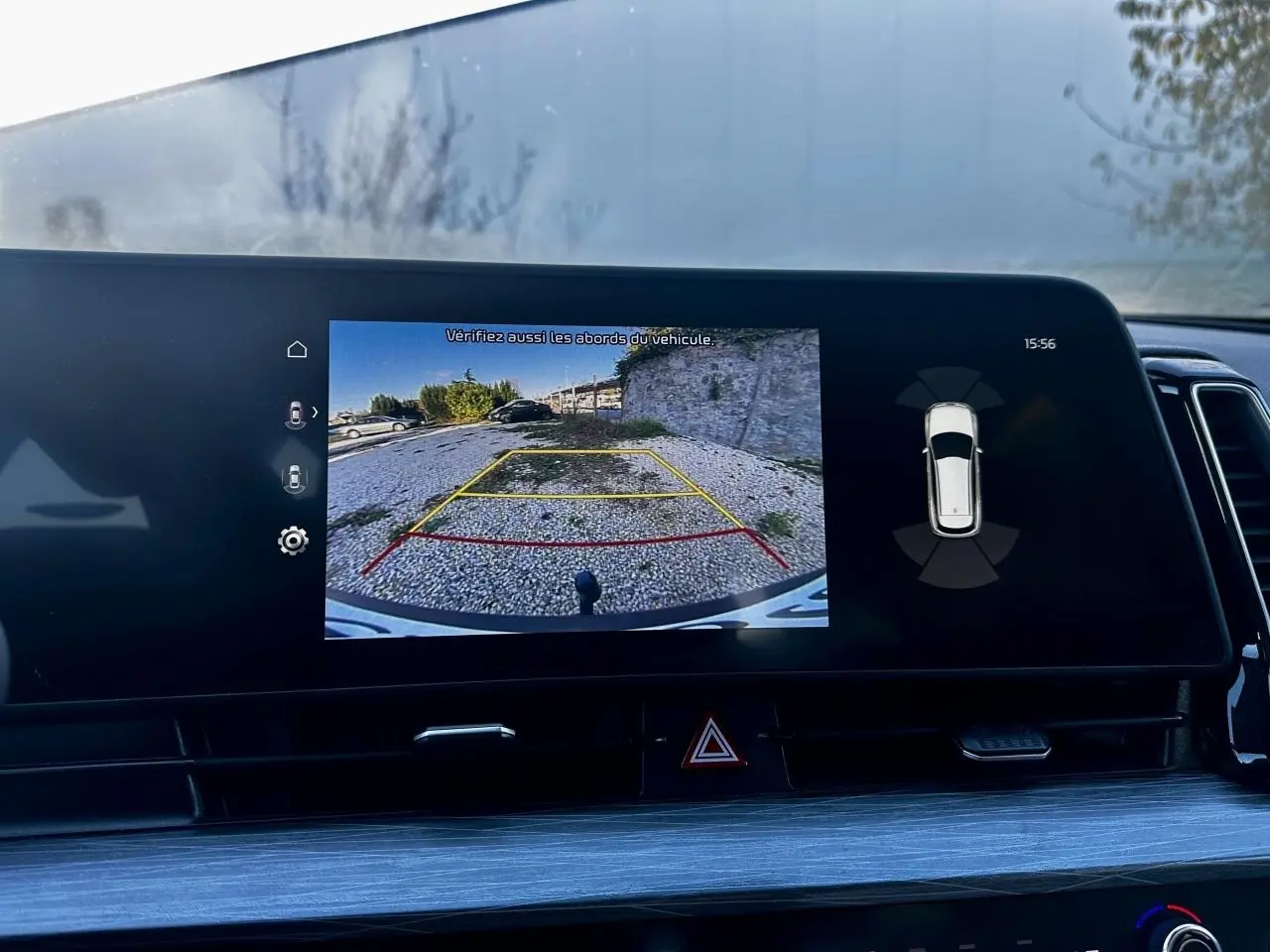 Écran tactile du Kia Sportage 2023 montrant la caméra de recul avec lignes de guidage sur fond noir intérieur.