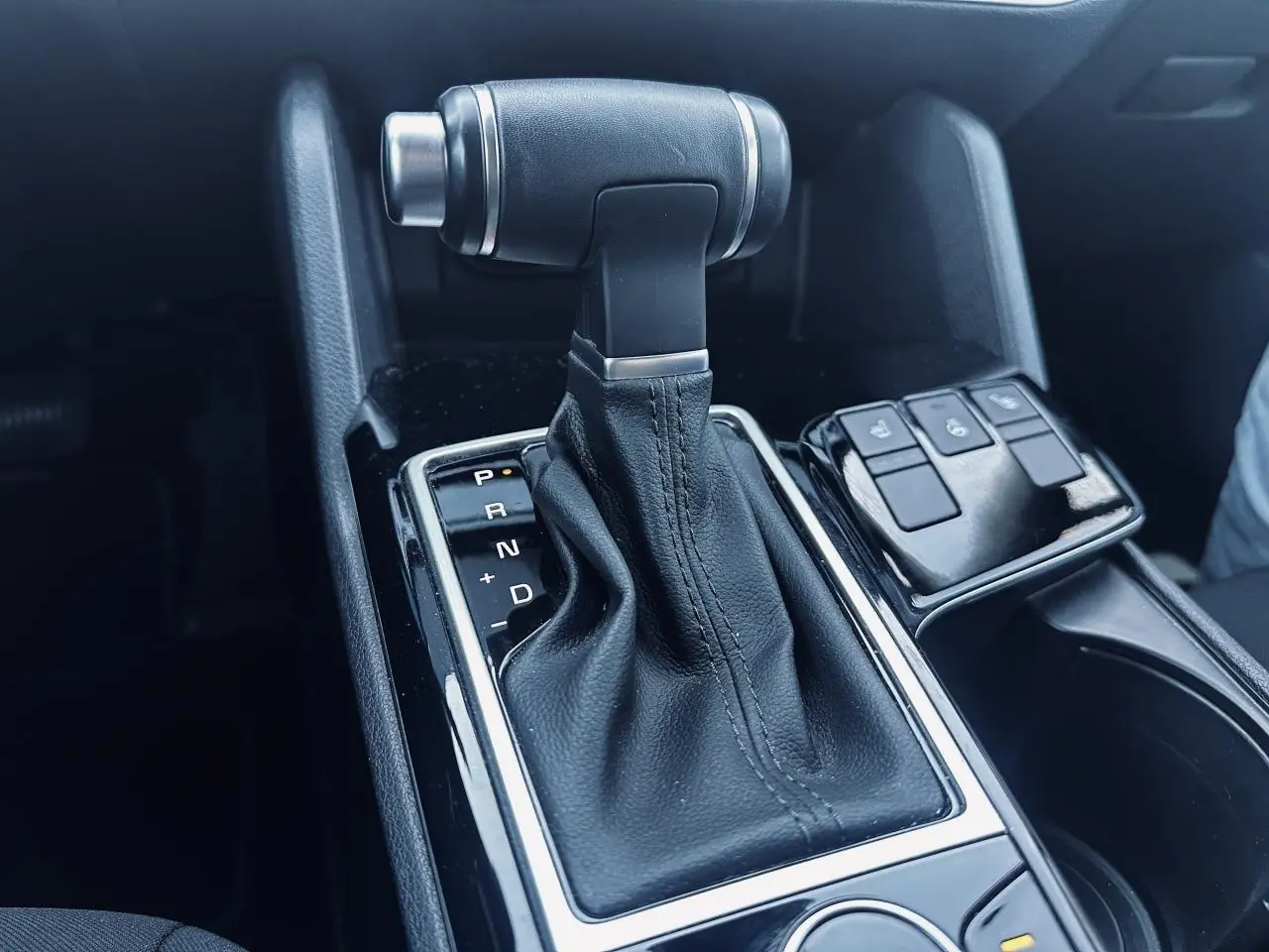 Le levier de vitesse automatique noir du Kia Sportage 2023, vue rapprochée de la console centrale avec boutons de contrôle.