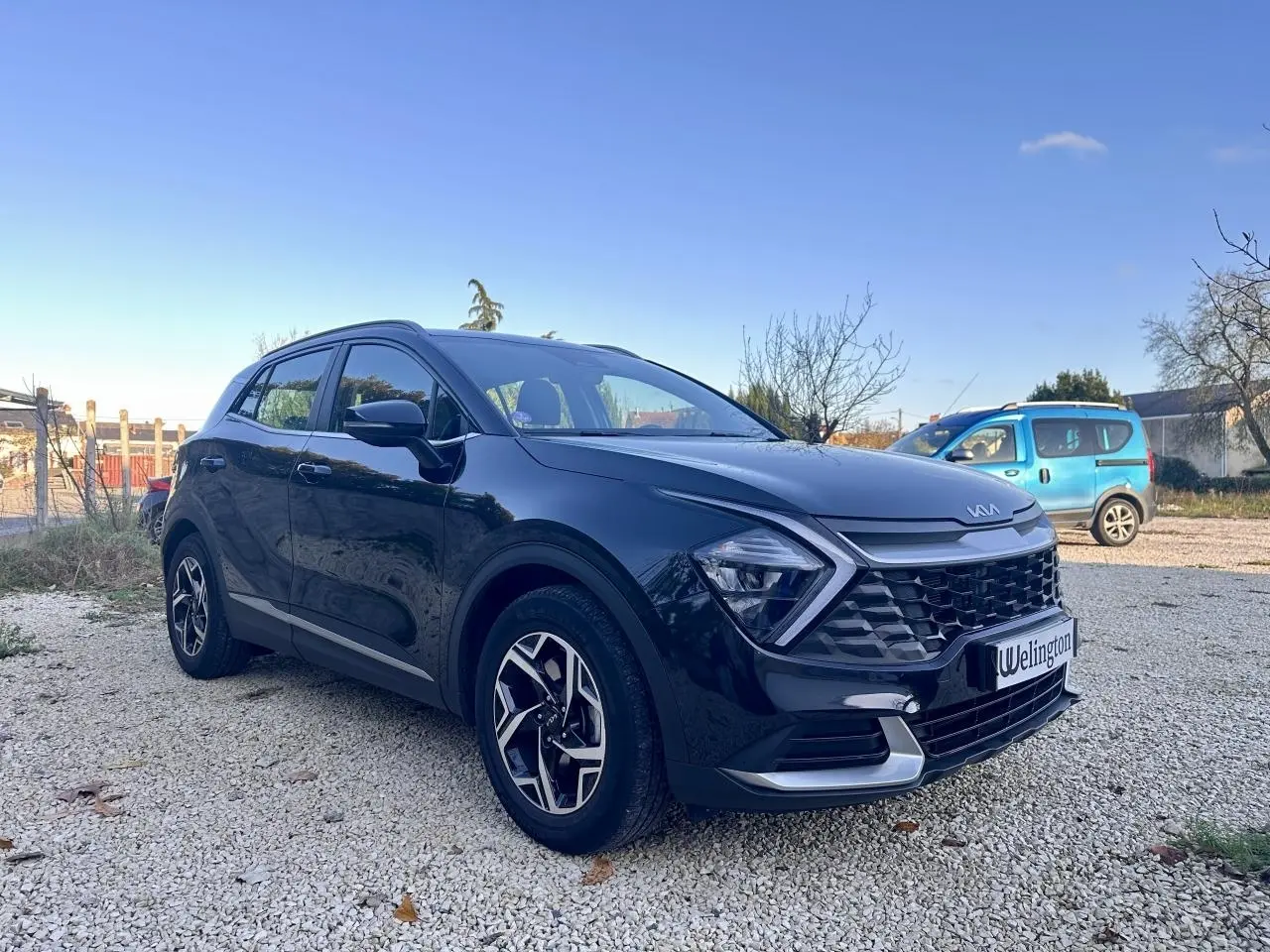 Kia Sportage noir vu en 3/4 avant droit, avec calandre distinctive et jantes alliage modernes.
