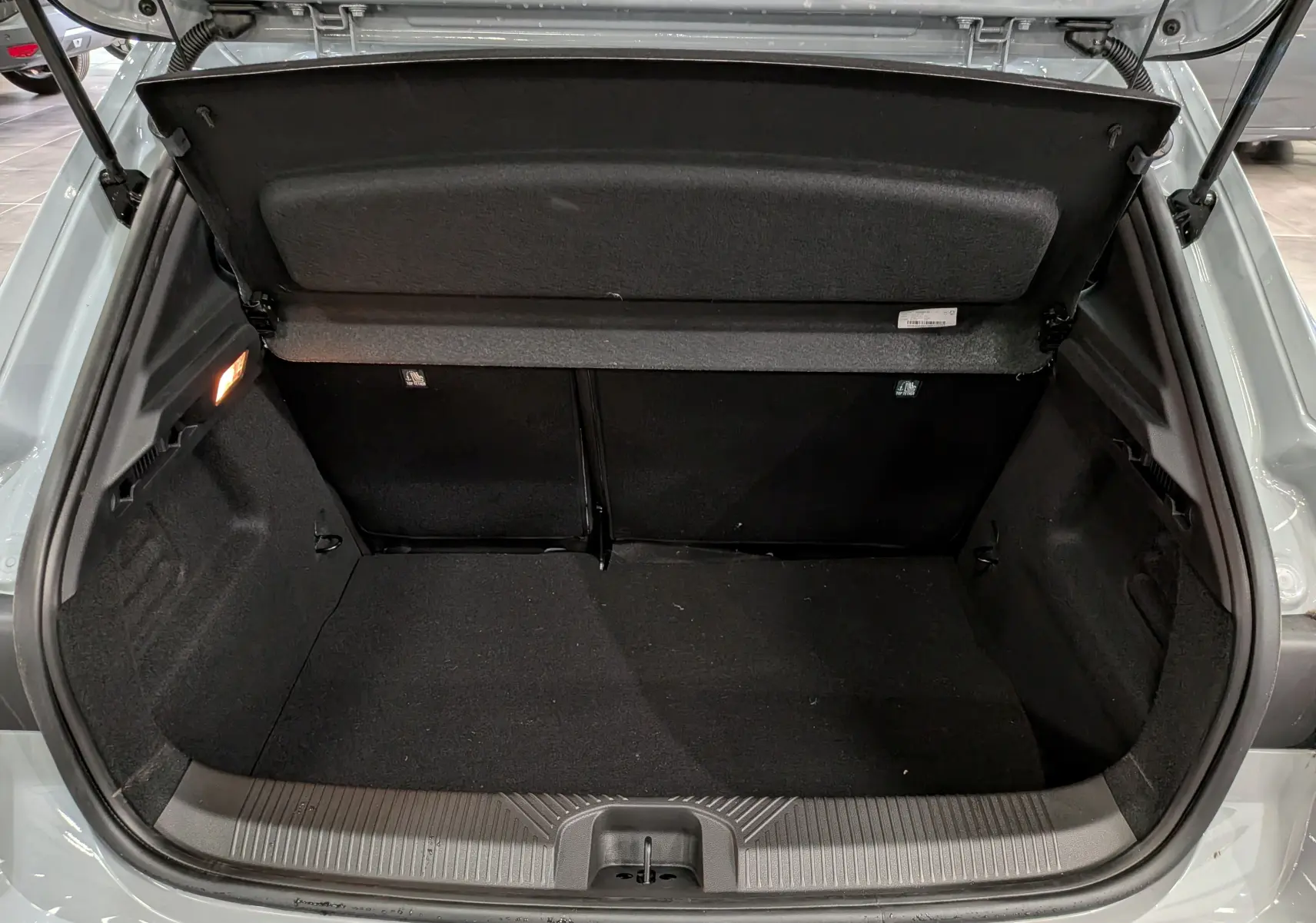 Coffre ouvert vu de l'arrière d'une Renault Clio VI TCe 115 Gris Rafale, montrant l'espace de chargement vide.