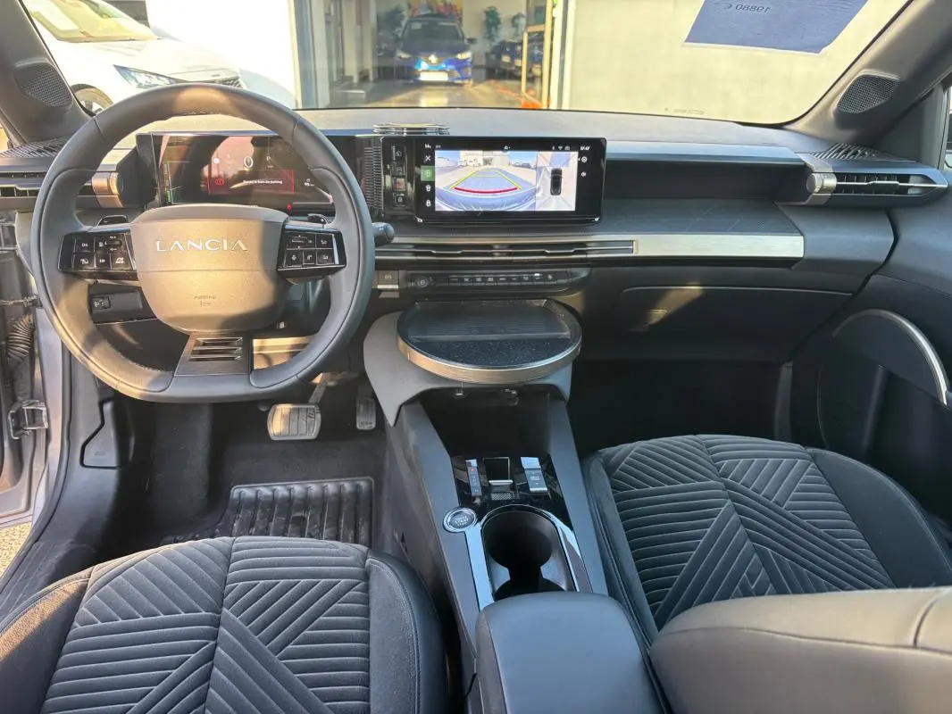 Vue intérieure avant de la Lancia Ypsilon gris, avec tableau de bord moderne et écran tactile affichant la caméra de recul.