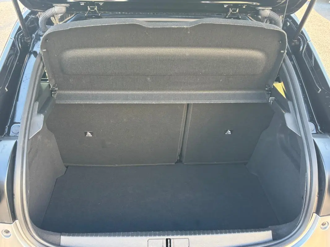 Vue plongeante sur le coffre ouvert d'une Lancia Ypsilon gris 2025, montrant un espace de rangement propre et vide.