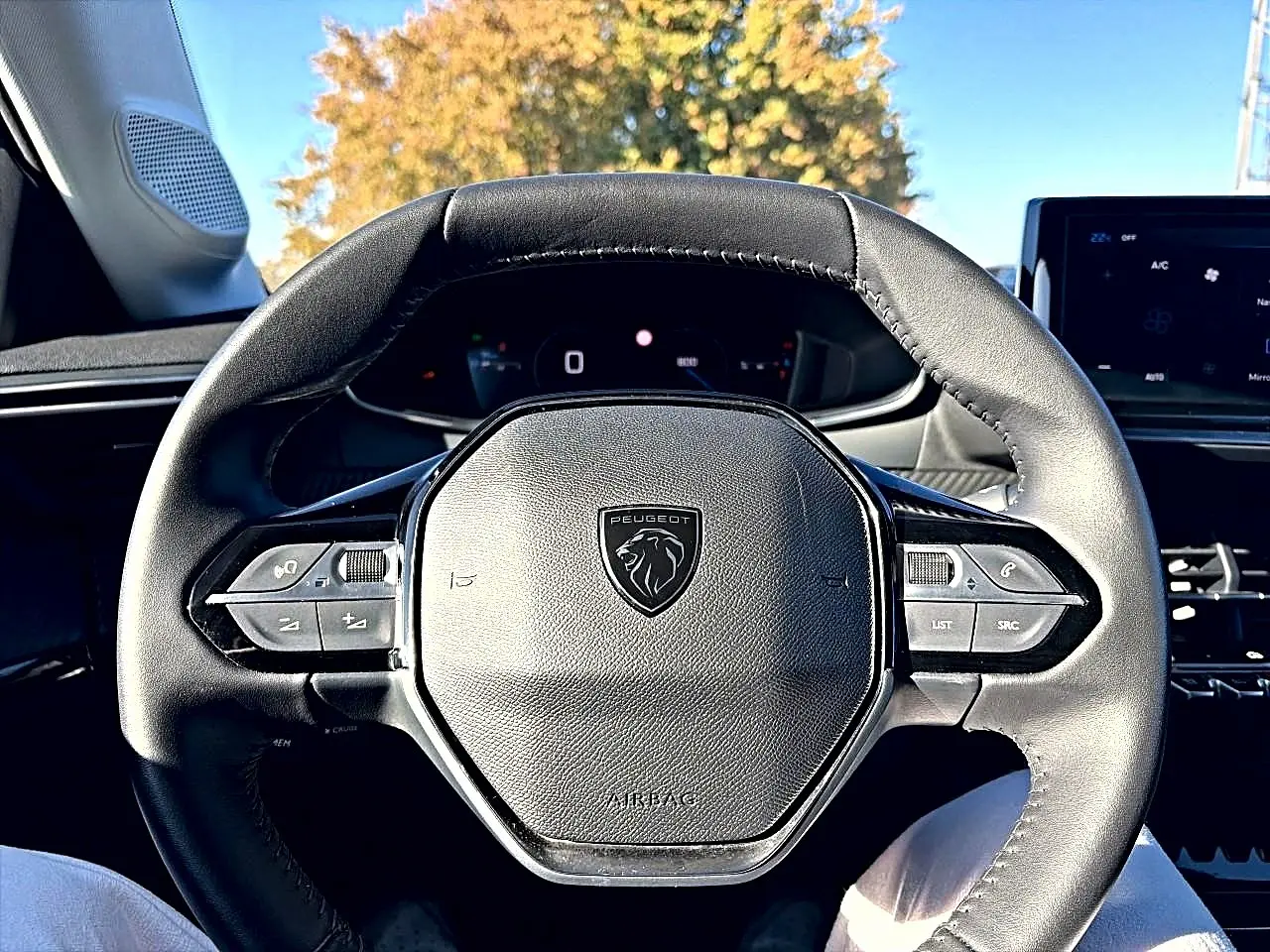 Vue rapprochée du volant cuir noir de la Peugeot 208 1.2 100 allure avec commandes intégrées et tableau de bord digital.