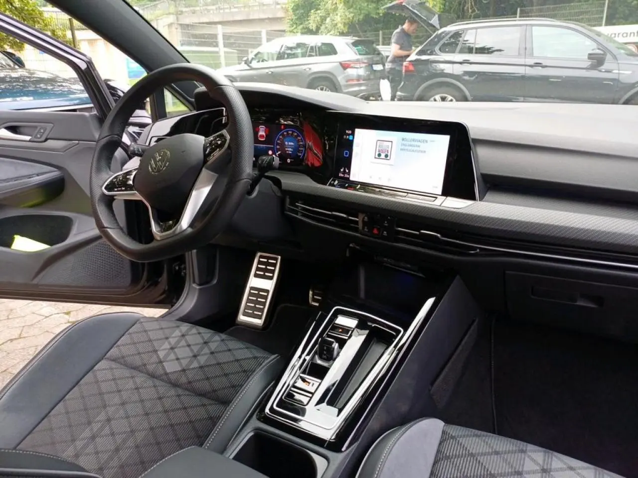 Vue intérieure côté conducteur de la Volkswagen Golf VIII R-Line noire, avec tableau de bord digital et volant cuir multifonctions.
