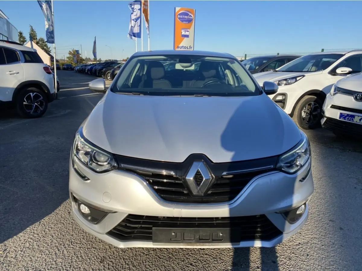 Vue de face d'une Renault Mégane Sedan gris platine avec projecteurs antibrouillard et calandre noire brillante.