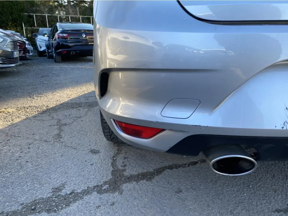 Gros plan sur le coin arrière droit gris platine d'une Renault Mégane avec sortie d'échappement visible.