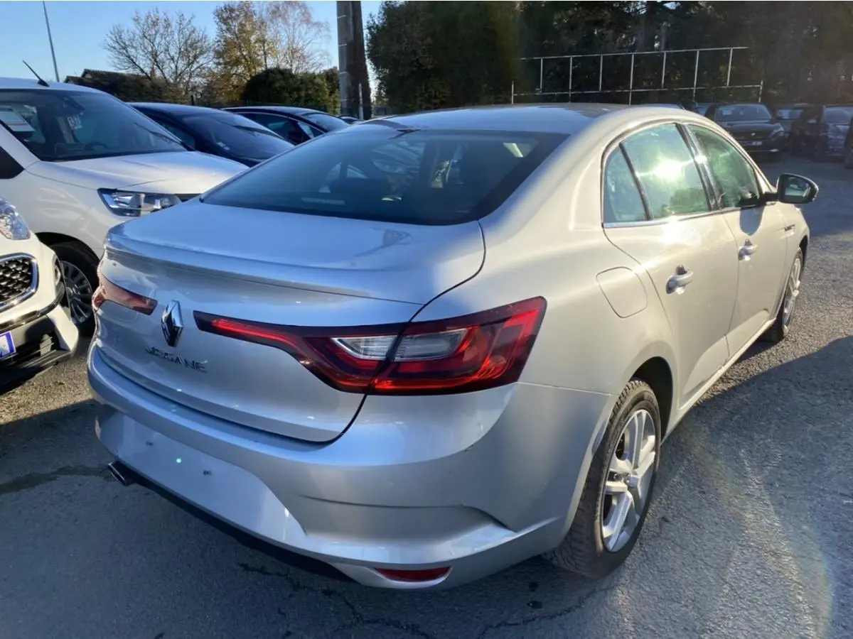 Vue 3/4 arrière droite d'une Renault Mégane Sedan gris platine, avec feux arrière LED et jantes alliage visibles.