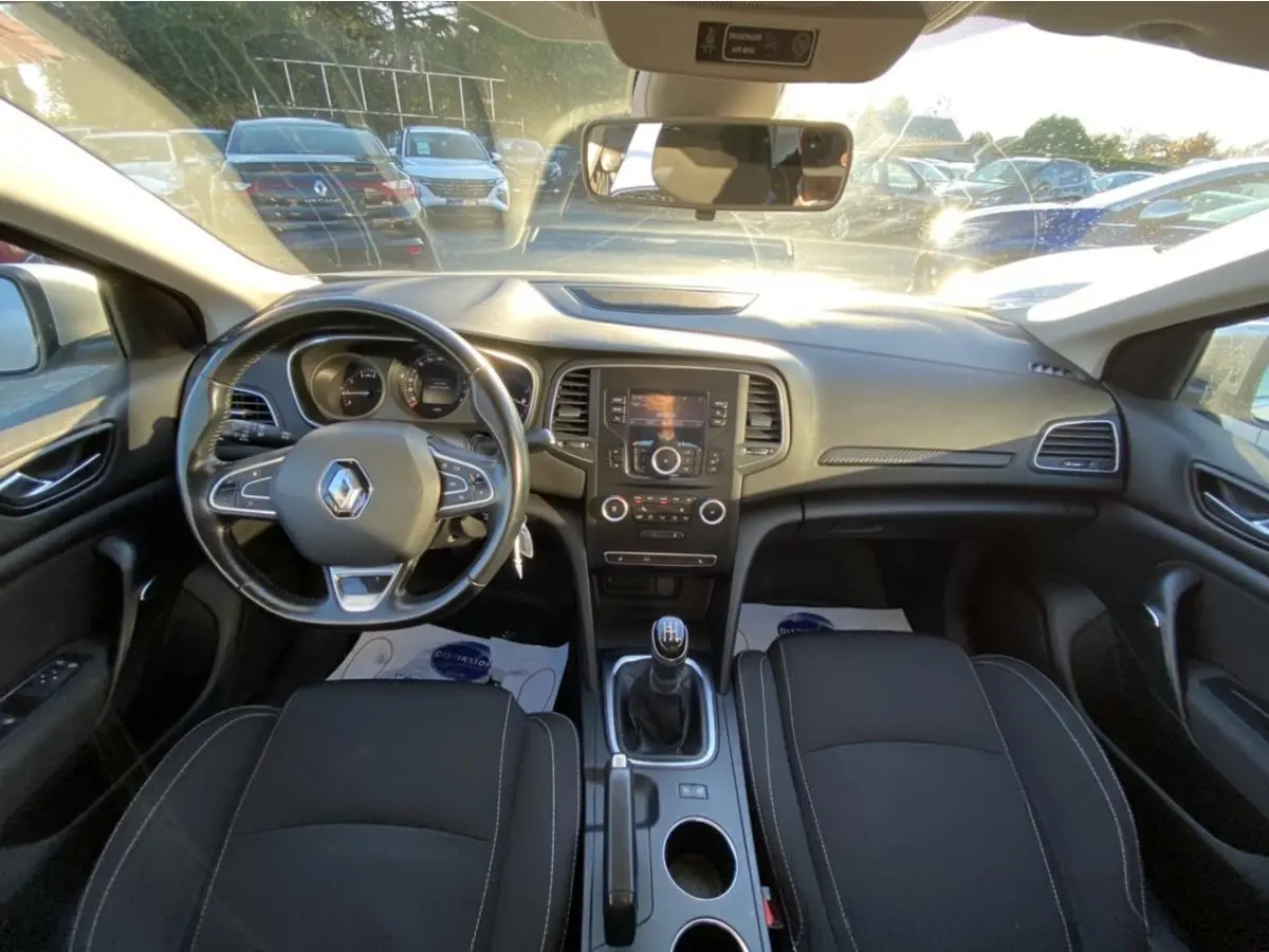 Vue intérieure avant de la Renault Mégane gris platine 2017, avec volant multifonctions et boîte manuelle.