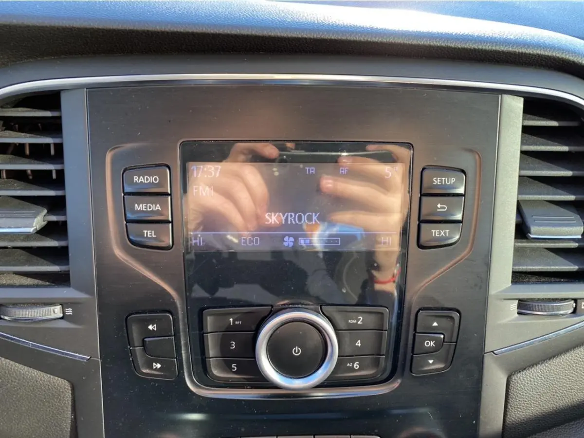 Détail de la console centrale de la Renault Mégane gris platine, avec écran radio affichant la station Skyrock.