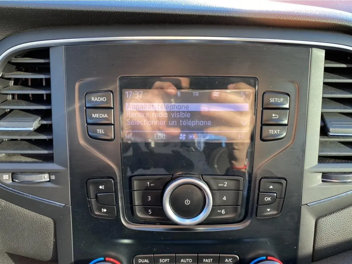 Gros plan sur la console centrale de la Renault Mégane gris platine, affichant l'écran multimédia et les commandes audio.