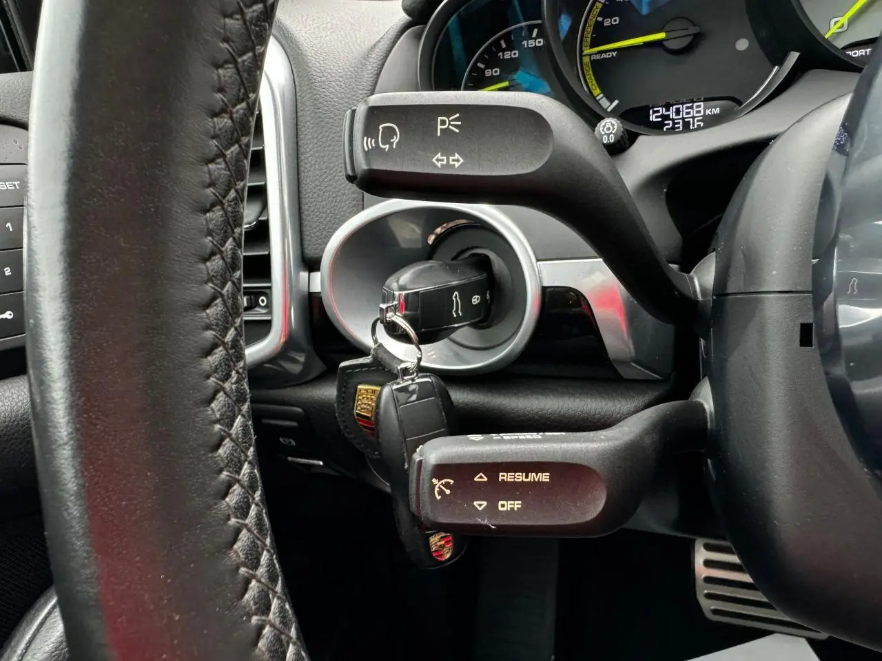 Gros plan sur le volant cuir et le contacteur avec clé Porsche dans le tableau de bord du Cayenne noir 2017.
