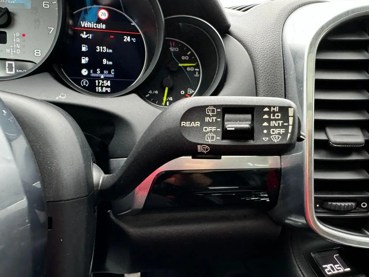 Gros plan sur le commodo d'essuie-glace à droite du volant dans l'habitacle noir du Porsche Cayenne hybride 2017.