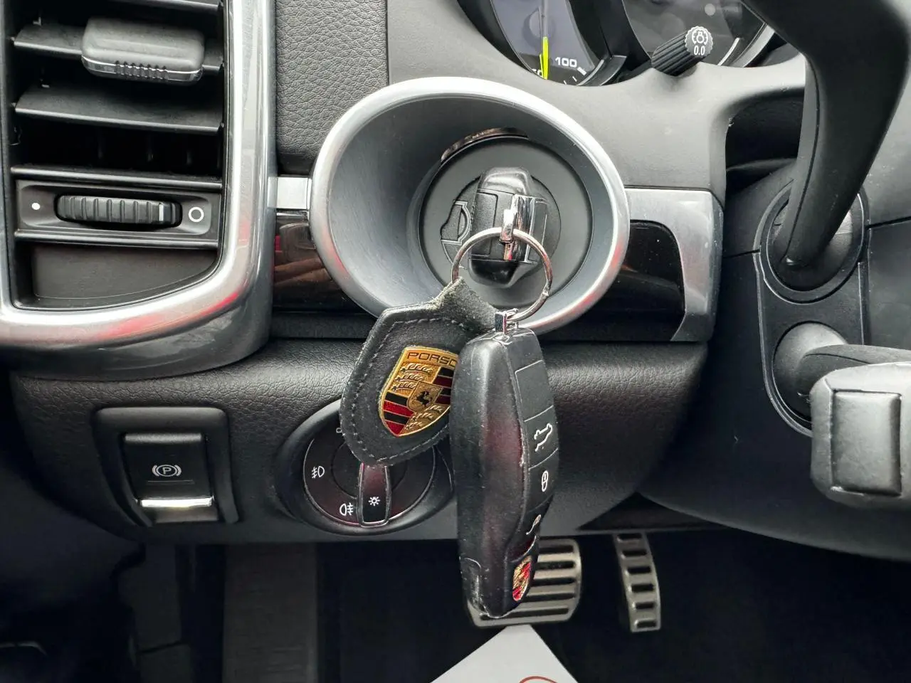 Gros plan sur le contacteur avec clé Porsche suspendue dans l'habitacle noir du Cayenne 2017.