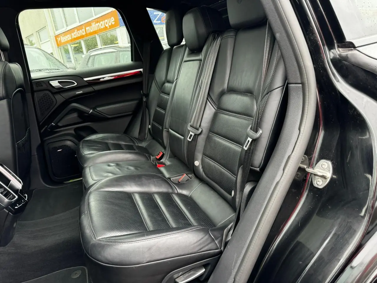 Vue côté droit sur les sièges arrière en cuir noir du Porsche Cayenne S E-Hybrid 2017 avec portière ouverte.