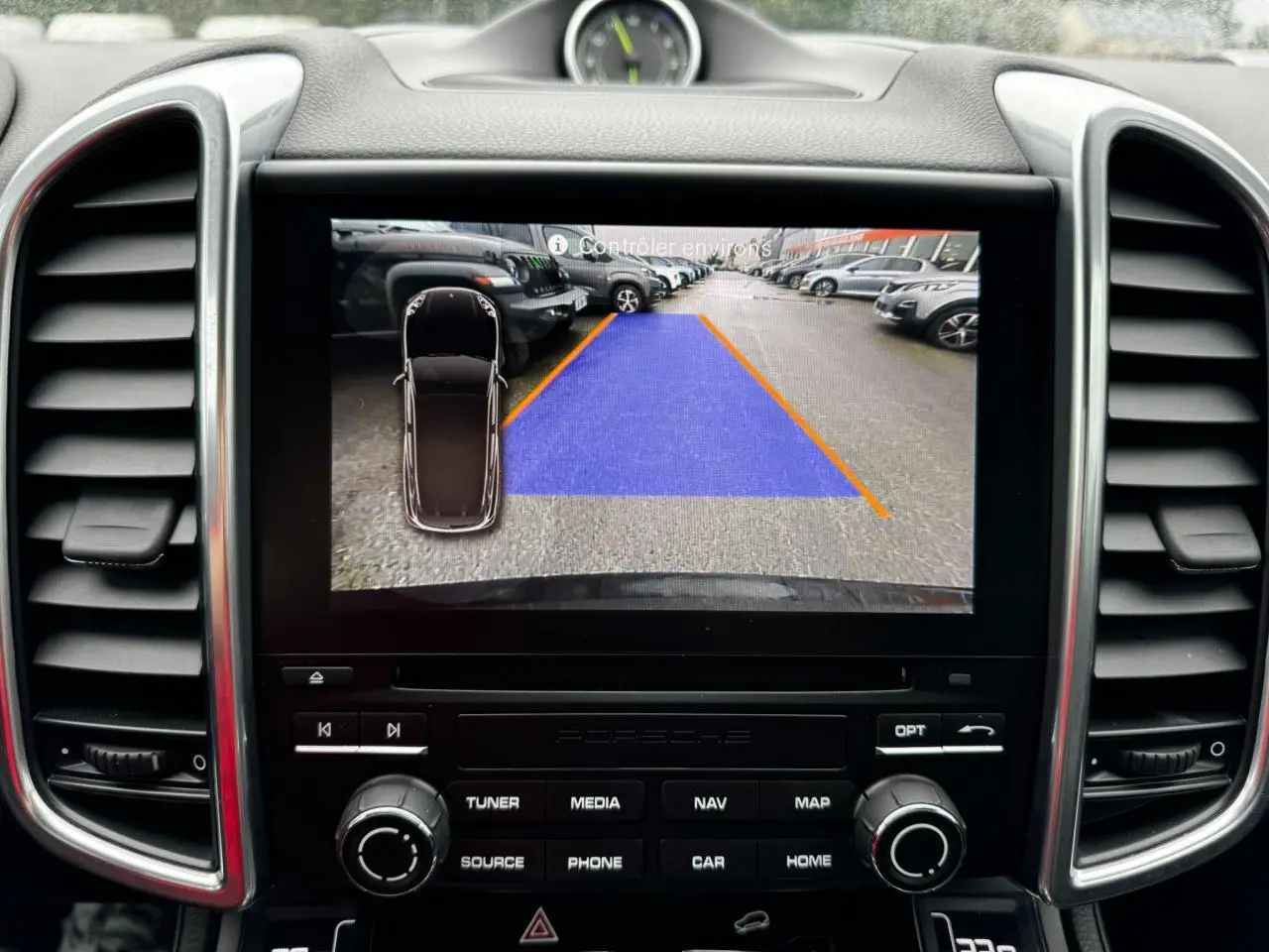 Affichage caméra de recul sur écran central du tableau de bord d'un Porsche Cayenne noir, vue intérieure frontale.