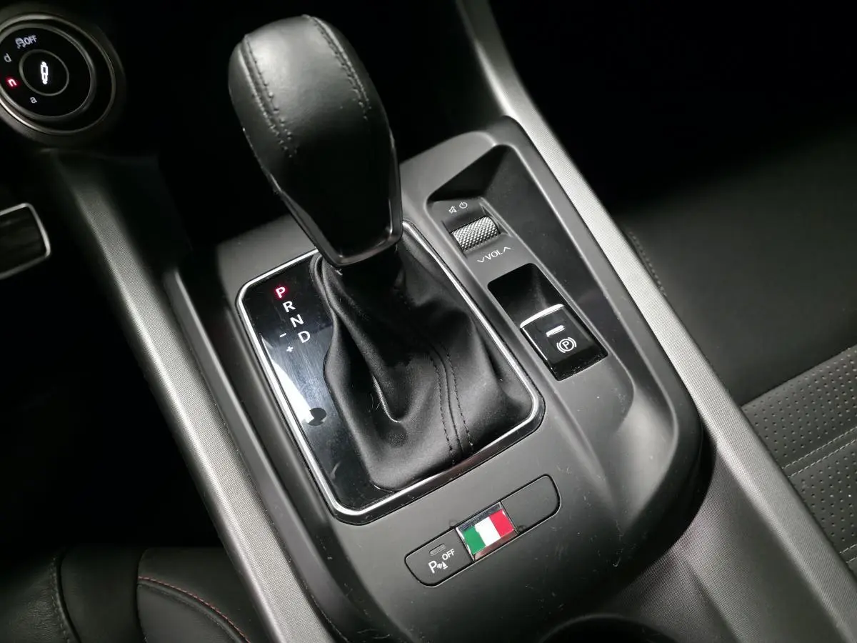 Gros plan sur la console centrale de l'Alfa Romeo Tonale 2024, levier de vitesse cuir noir et drapeau italien.